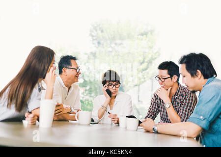 Groupe diversifié de cinq affaires asiatiques en personne à la réunion de l'équipe café ou moderne bureau stratégique. Remue-méninges, propriétaire de petite entreprise, parler de la famille, Banque D'Images