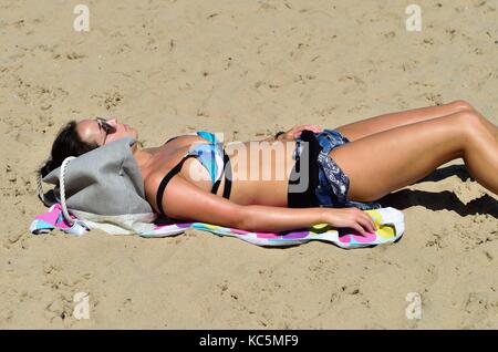 Femme avec un patch de sable à profiter du soleil sur Chicago's Oak Street Beach. Chicago, Illinois, USA. Banque D'Images