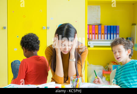 Obtenir de l'enseignant de tête avec deux enfants naughty en classe à l'école maternelle Banque D'Images