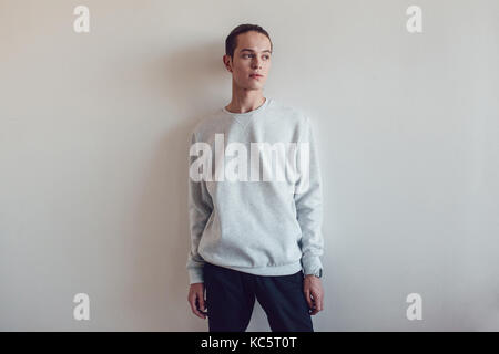 Jeune homme en gris noir sur fond blanc. maquette. Banque D'Images