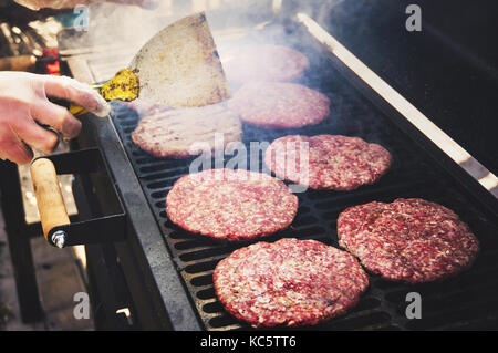 Burger congelé dans la main prêt à la préparation faire cuire. ronde de galettes de viande hachée crue rôti sur une grille métallique. Banque D'Images