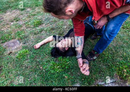 L'homme aidant la jeune femme ivre couchée sur le sol a trop bu Banque D'Images