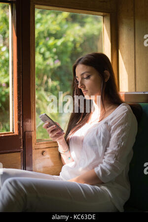 Jolie jeune femme à un petit train à l'aide de son portable Banque D'Images