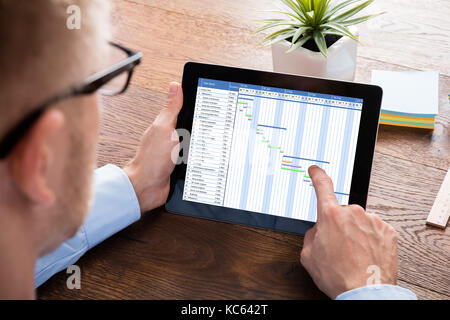 Businessman working on gantt sur tablette numérique au bureau en bois Banque D'Images