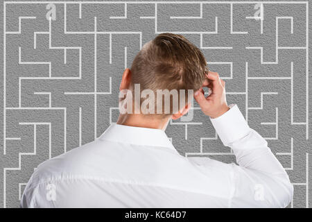 Young businessman looking at confus essayant de labyrinthe pour résoudre les casse-tête Banque D'Images