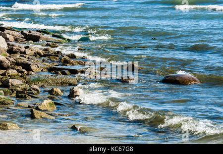 Côte rocheuse avec de petites vagues entrant et le barattage sur pierres humides. Banque D'Images