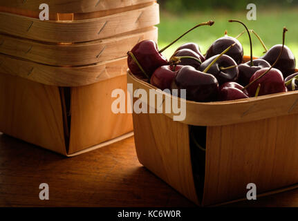Panier plein de cerises sur la table en bois Banque D'Images