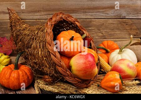 Thanksgiving cornucopia rempli de citrouilles et de fruits contre un arrière-plan en bois rustique Banque D'Images