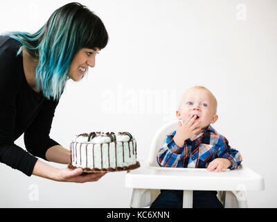Mother holding gâteau d'anniversaire pour son (12-17 mois) Banque D'Images
