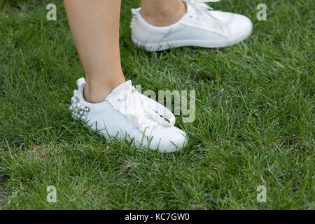 Milan, Italie - 22 septembre 2017 : modèle portant une paire de chaussures de sport blanc élégant décoré de perles au cours de la parade, photographié sur armani Banque D'Images