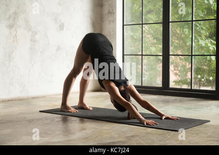 Jeune femme séduisante dans adho mukha svanasana, pose d'atelier Banque D'Images