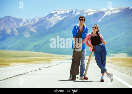 Heureux couple planche longboard sur route Banque D'Images
