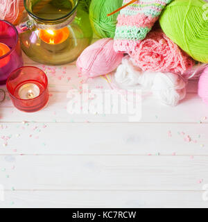 Bougies, fils, tricot sur un fond blanc. bois couleurs rose et vert. Banque D'Images