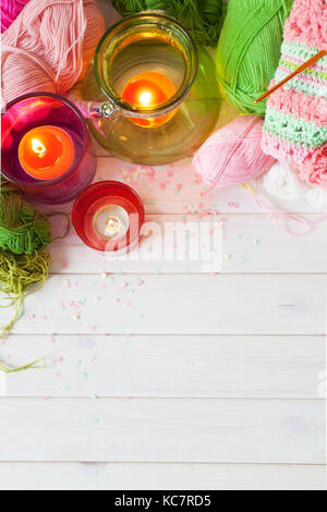 Bougies, fils, tricot sur un fond blanc. bois couleurs rose et vert. Banque D'Images