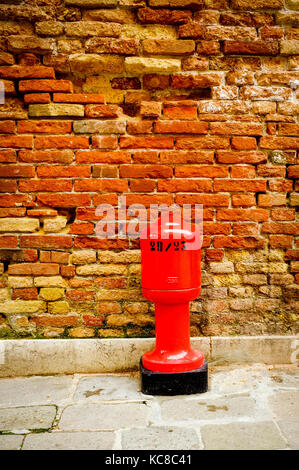 Une bouche d'incendie rouge en face d'un mur de briques en ruine Banque D'Images