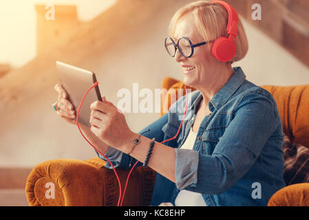 Femme d'un âge à l'aide de sa joyeuse tablet Banque D'Images