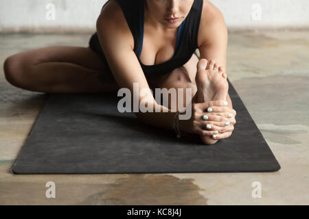 Jeune femme sportive en janu sirshasana pose, fond studio Banque D'Images