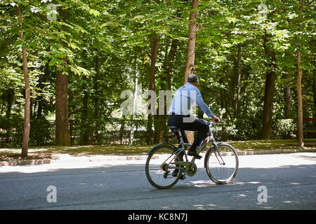 L'homme d'affaires à cheval sur un vélo dans le parc. mode de vie sain Banque D'Images