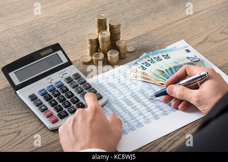 Close-up of a businessman analyse rapport financier sorcière pile de pièces Banque D'Images