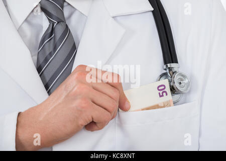 Close-up of Male Doctor part mettre l'argent dans la poche Banque D'Images