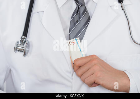 Close-up of male doctor part mettre l'argent dans la poche Banque D'Images