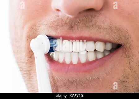 Close-up of Young Man dents avec brosse à dents électrique Banque D'Images