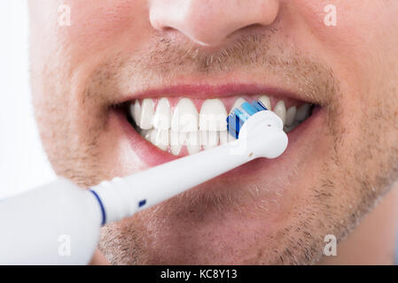 Close-up of Young Man dents avec brosse à dents électrique Banque D'Images