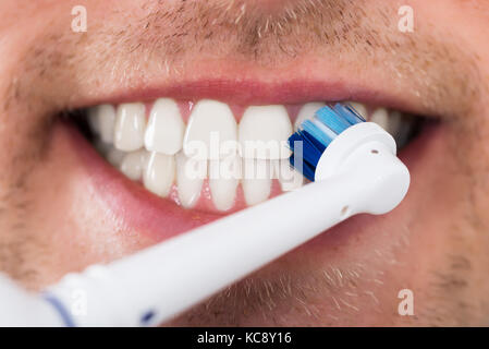 Close-up of Young Man dents avec brosse à dents électrique Banque D'Images