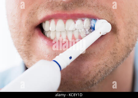 Close-up of Young Man dents avec brosse à dents électrique Banque D'Images