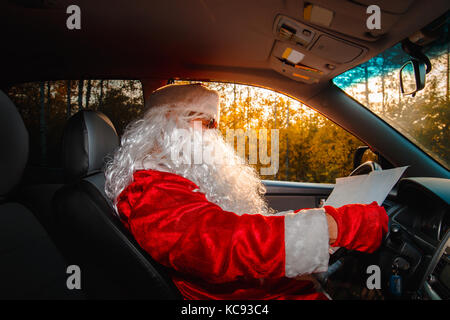 Père Noël authentique. Le père noël conduit une voiture à travers la forêt d'automne. en attente de noël. Banque D'Images