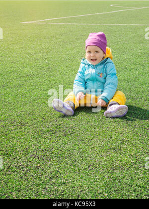 Petite fille enfant sur terrain de football, dans les vêtements de sport, de la formation, joue avec pelouse artificielle sur soccerball Banque D'Images