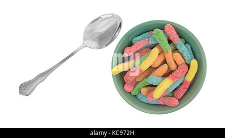 Vue de dessus d'une portion de sucre coloré dégustation aigre couché gummy worms dans un bol de petit-déjeuner avec une cuillère pour le côté isolé sur un fond blanc. Banque D'Images