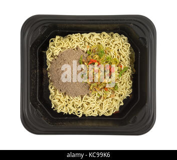 Vue de dessus du boeuf cru nouilles ramen aromatisé avec les assaisonnements et les légumes secs dans un bac allant au noir isolé sur un fond blanc. Banque D'Images