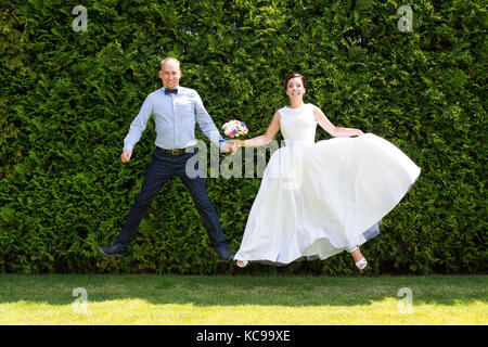 Mariée et le marié qui saute dans l'air. Heureux juste marié mariage jeune couple dans le parc. Banque D'Images