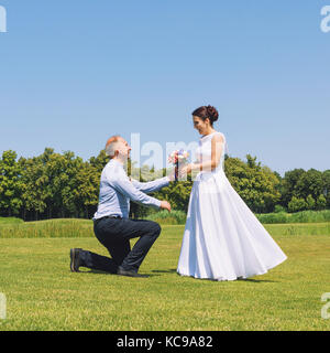 L'homme fait une proposition à sa copine pour se marier. proposition de mariage. L'amour et le mariage concept. young attractive cheerful couple dans le parc. Banque D'Images