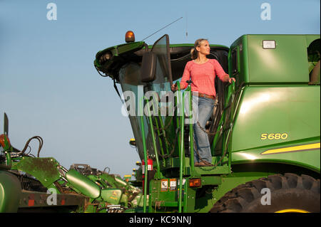 Une jeune PRODUCTRICE DONNE SUR LE TERRAIN DE SA MOISSONNEUSE-BATTEUSE JOHN DEERE AVANT LA RÉCOLTE DU BLÉ À LA FERME FAMILIALE PRÈS DE BRECKENRIDGE, DAKOT NORD Banque D'Images