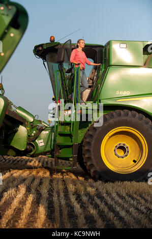 Une jeune PRODUCTRICE DONNE SUR LE TERRAIN DE SA MOISSONNEUSE-BATTEUSE JOHN DEERE AVANT LA RÉCOLTE DU BLÉ À LA FERME FAMILIALE PRÈS DE BRECKENRIDGE, DAKOT NORD Banque D'Images