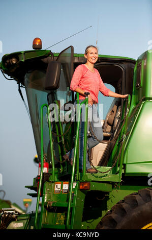 Une jeune PRODUCTRICE DONNE SUR LE TERRAIN DE SA MOISSONNEUSE-BATTEUSE JOHN DEERE AVANT LA RÉCOLTE DU BLÉ À LA FERME FAMILIALE PRÈS DE BRECKENRIDGE, DAKOT NORD Banque D'Images