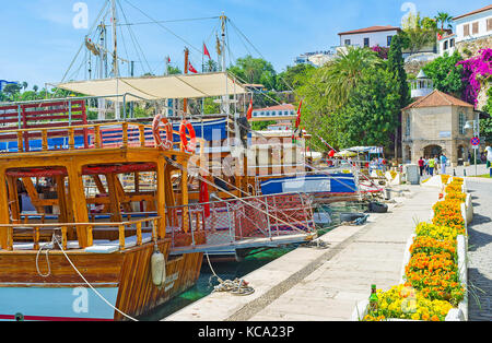 Antalya, Turquie - 12 mai 2017 : La promenade le long des bateaux de touristes dans le vieux port avec une vue sur la mosquée iskele historique, situé au pied de la falaise Banque D'Images