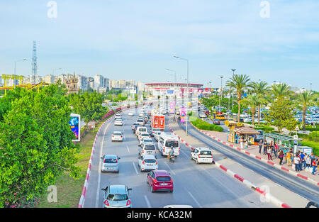 Antalya, Turquie - 12 mai 2017 : le trafic lourd dans boulevard Ataturk, entouré de verdure, avec la grande roue et Antalya stadium sur le backg Banque D'Images