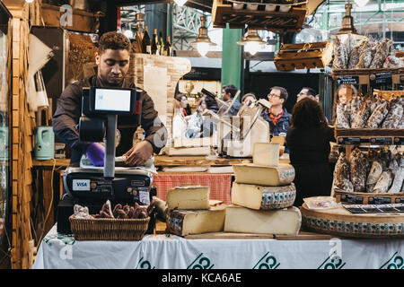 Le vendeur d'un poids et l'emballage du fromage à l'épicerie sont à Borough Market, un des plus grands et les plus anciens marchés alimentaires de Londres. Banque D'Images