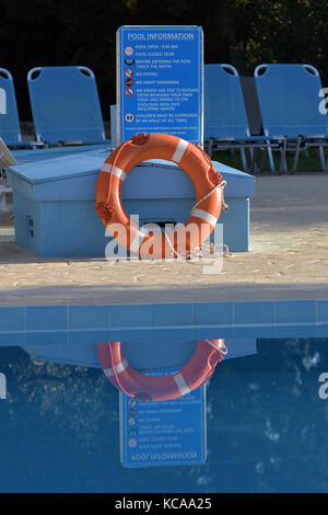 Une bouée de sauvetage ou flottant sur le côté de l'aide d'une piscine vide dans un hôtel à Corfou, Grèce. Transats et chaises longues à côté d'une piscine. Banque D'Images