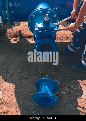 Les mains des travailleurs de la valve de vissage avec les écrous à nouveau dring les canalisations d'eau. aune de l'eau avec la construction de nouveaux robinets-vannes et la réduction membre. pipe pos e Banque D'Images