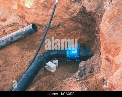 Processus de réparation de canalisation d'eau souterraine les tubes en plastique noir. dans la tranchée de sable a rejoint avec les tubes en acier, avec des co-membre et scr Banque D'Images