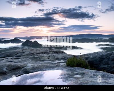 Vue sur le pic rocheux de grès humide dans la vallée de la forêt, l'aube, soleil à l'horizon. hills est passé de l'arrière-plan flou Banque D'Images