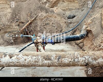 Fouille. vieux 500mm boire de l'eau tuyau avec 150mm bras de virage avec robinets-vannes, raccords tubes corrodés rejoindre. tuyauterie avant réparation. asphal Banque D'Images