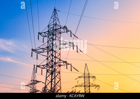 Pylônes à haute tension et la transmission des lignes de transport d'électricité sur le fond de ciel bleu. Banque D'Images