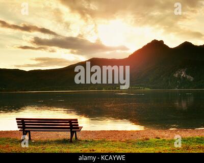 Banc vide à Spring Mountain Lake. La côte avec des montagnes à l'horizon et dans l'eau miroir. tons vintage photo. Banque D'Images