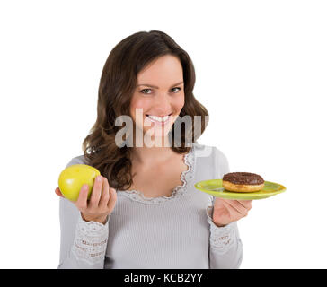 Jeune femme tenant une assiette de pomme verte et de donut sur fond blanc Banque D'Images