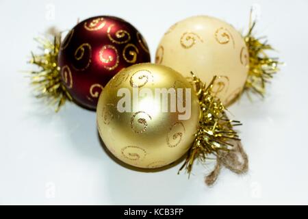 Trois décorations de noël multicolores en forme de ballon, peint avec des motifs d'or. une composition de nouvel an jouets sur un livre blanc backgroun Banque D'Images